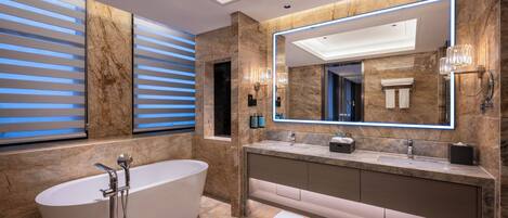 A modern bathroom with a freestanding bathtub, a large mirror, and a marble-tiled vanity.