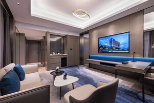 Una sala de estar moderna con un televisor de pantalla plana grande, un sofá, una mesa de centro y una zona de estar con un banco iluminado en azul.