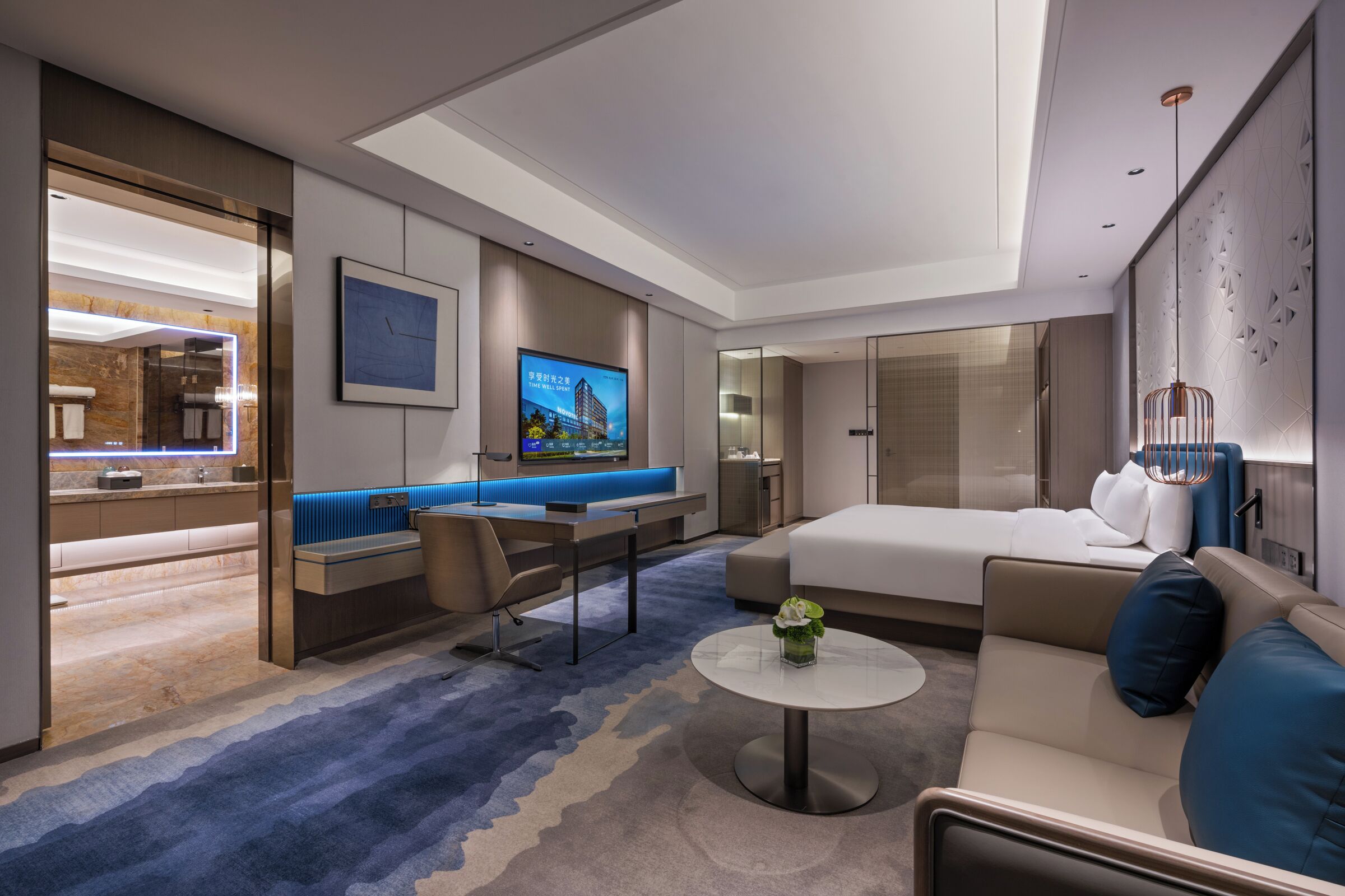 Ein modernes Hotelzimmer mit einem großen Bett, einer Couch, einem Schreibtisch und einem Fernseher.
