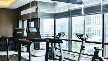 A modern gym with treadmills, stationary bikes, and a rowing machine.