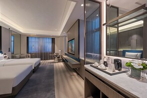Een moderne hotelkamer met een groot bed, een bureau, een zithoek en een grote spiegel.