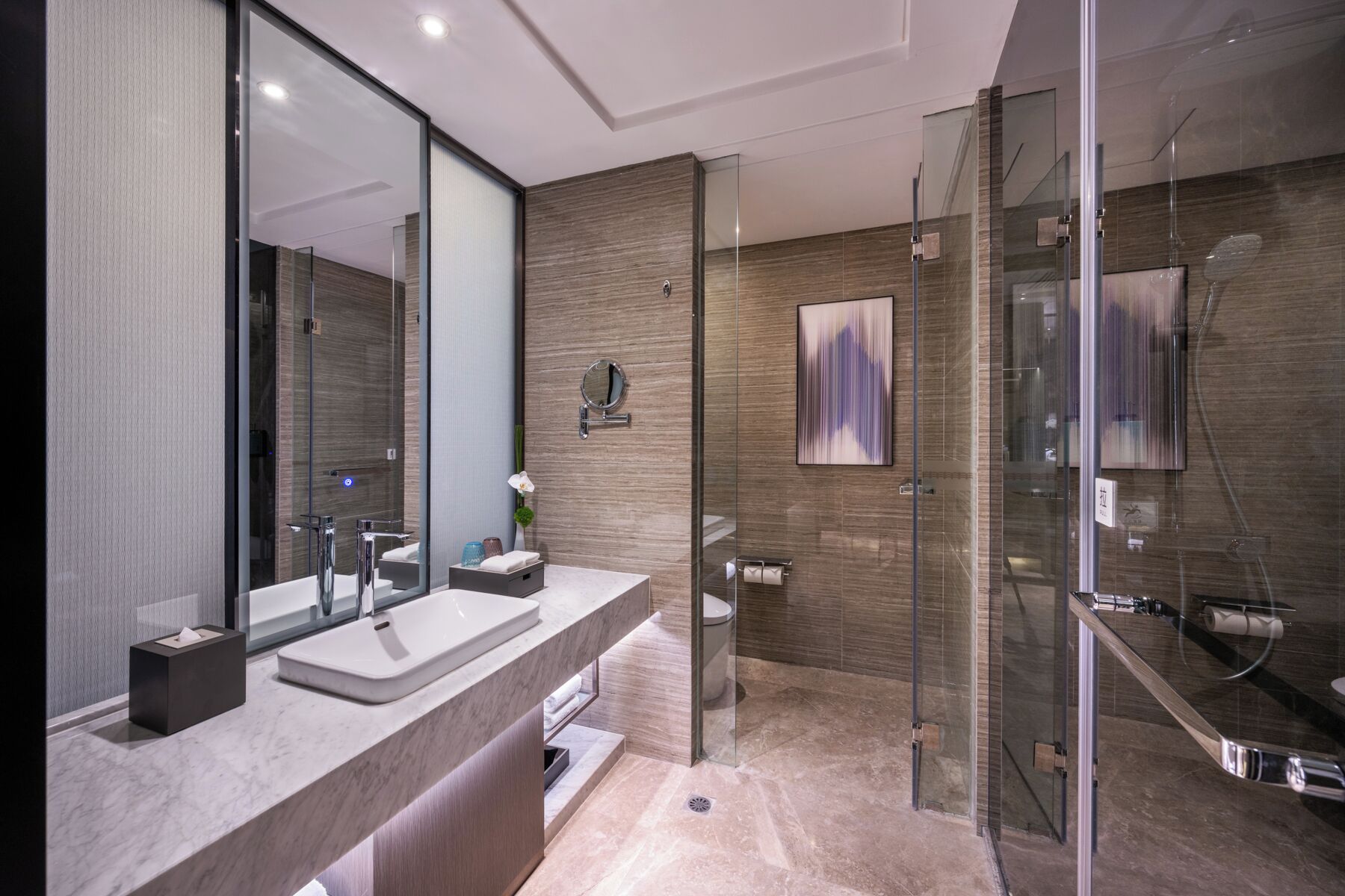 A modern bathroom with a glass shower enclosure, a large mirror, and a marble countertop.
