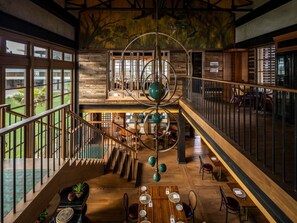 A spacious interior with a central staircase, wooden flooring, and a dining area with tables and chairs. - South Palms Resort And Spa Panglao - Mgallery Collection (Panglao)