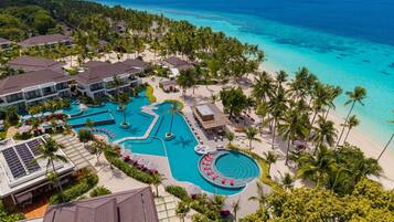 Un resort con una amplia piscina, playa y vistas al océano.