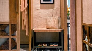A hallway with a wooden bench, a hanging coat rack, and a framed picture on the wall.