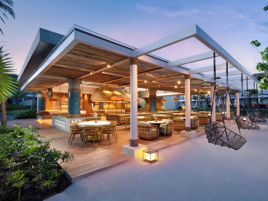 An outdoor dining area with tables and chairs, a covered seating area, and hanging chairs.