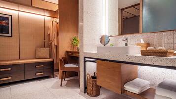 A modern bathroom with a wooden vanity, a round mirror, a sink, and a bench.