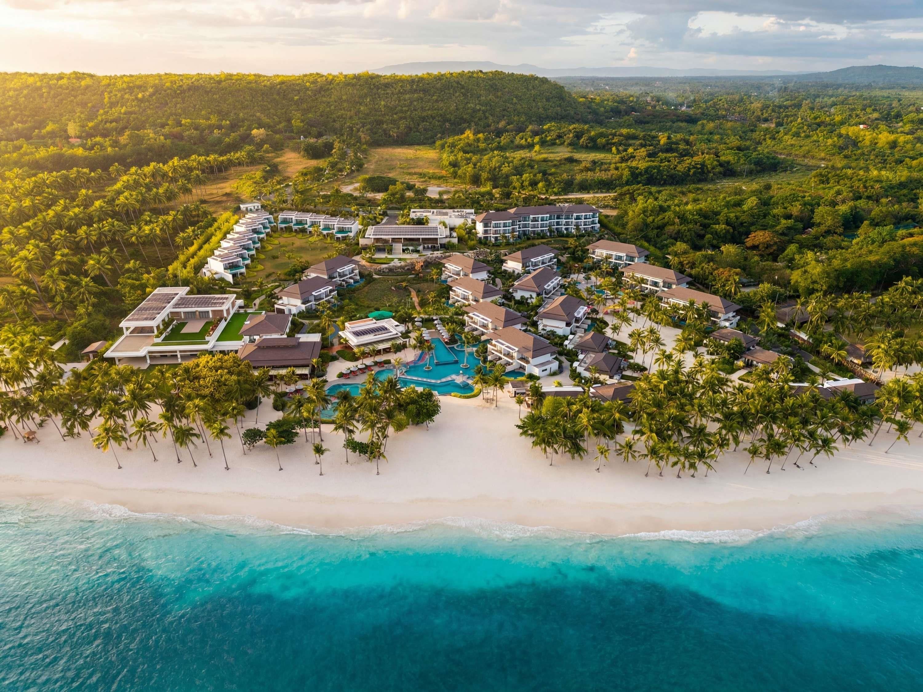 A resort with multiple buildings, a swimming pool, and a beachfront.
