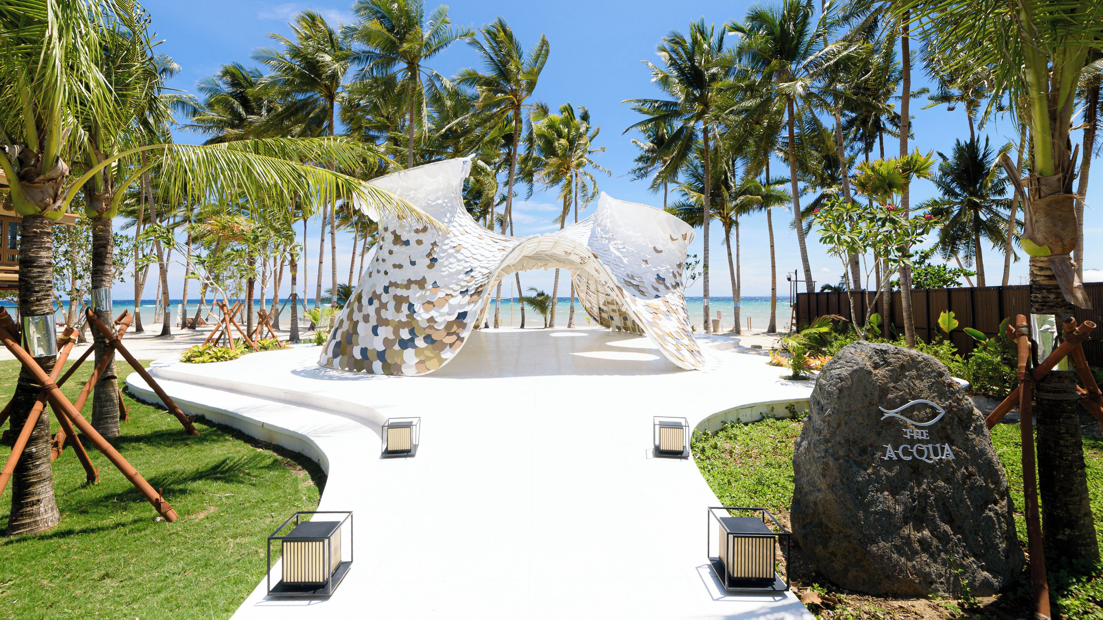 A beachside pathway leading to a decorative archway with a view of the ocean.
