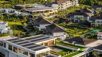 A modern resort with multiple buildings, solar panels, and lush greenery.