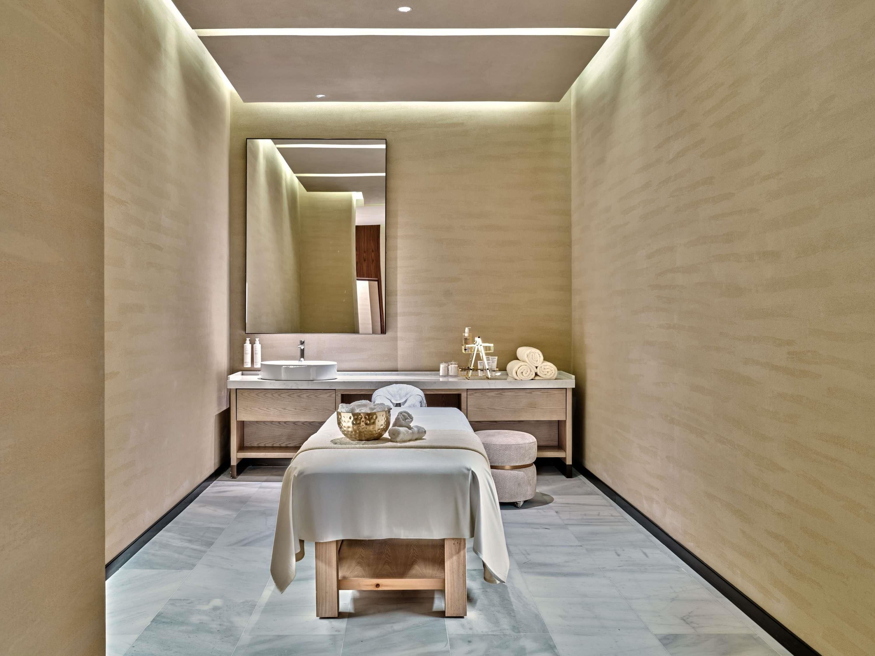 Un baño moderno con un espejo grande, un lavabo redondo, un banco y un perchero para toallas.