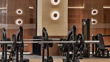 A modern gym with weightlifting equipment and mirrors on the walls.