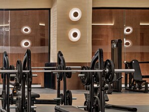 A modern gym with weightlifting equipment and mirrors on the walls.