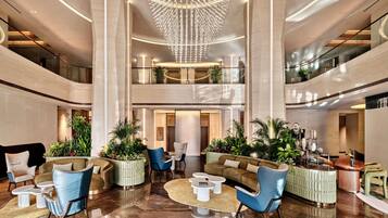 Un lobby espacioso con techo alto, muebles modernos y un candelabro central.