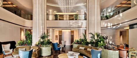 Un lobby espacioso con techo alto, muebles modernos y un candelabro central.