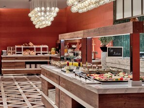 Montaje de bufé con diferentes opciones de comida, un cartel que indica una estación de huevos y un suelo con diseño.