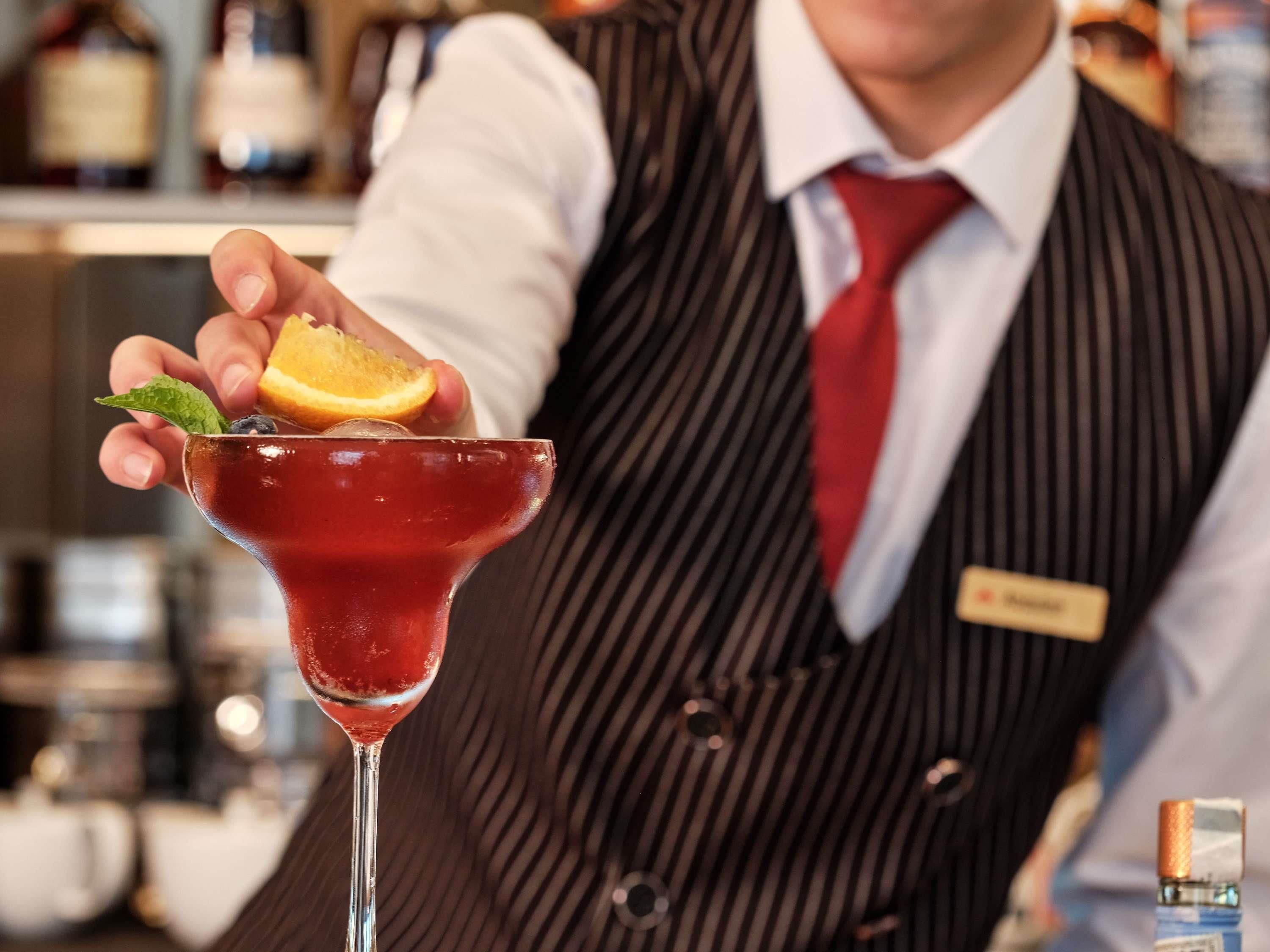 Un barman sosteniendo una copa de cóctel con una guarnición.