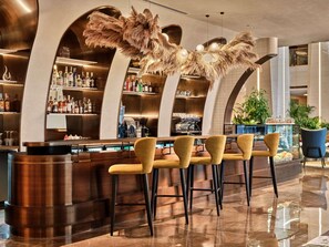 A modern bar area with a central counter, bar stools, and shelves stocked with bottles. - Swissôtel Tashkent (Tashkent)