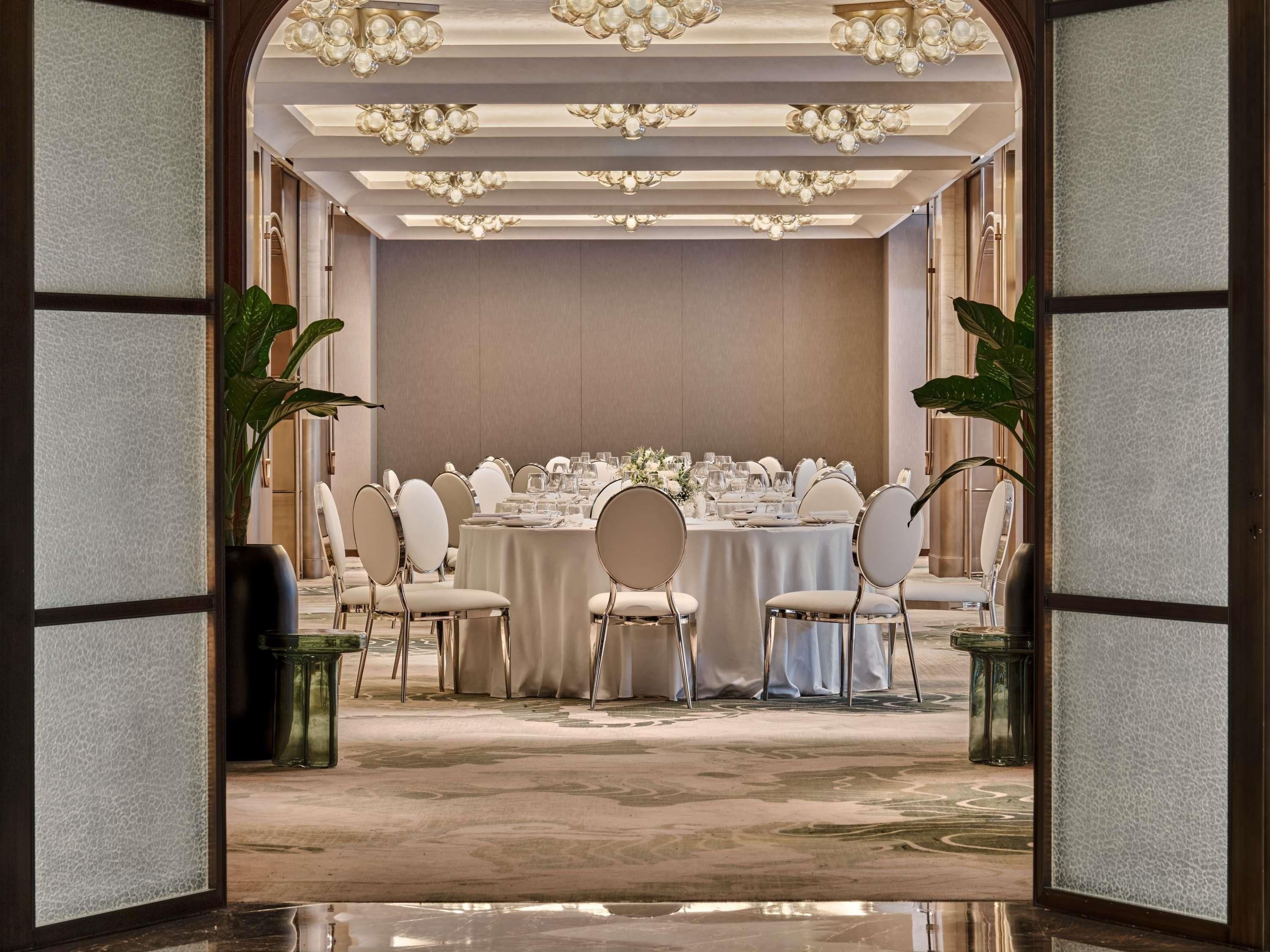 Un comedor formal con una mesa redonda, sillas blancas y candelabros.