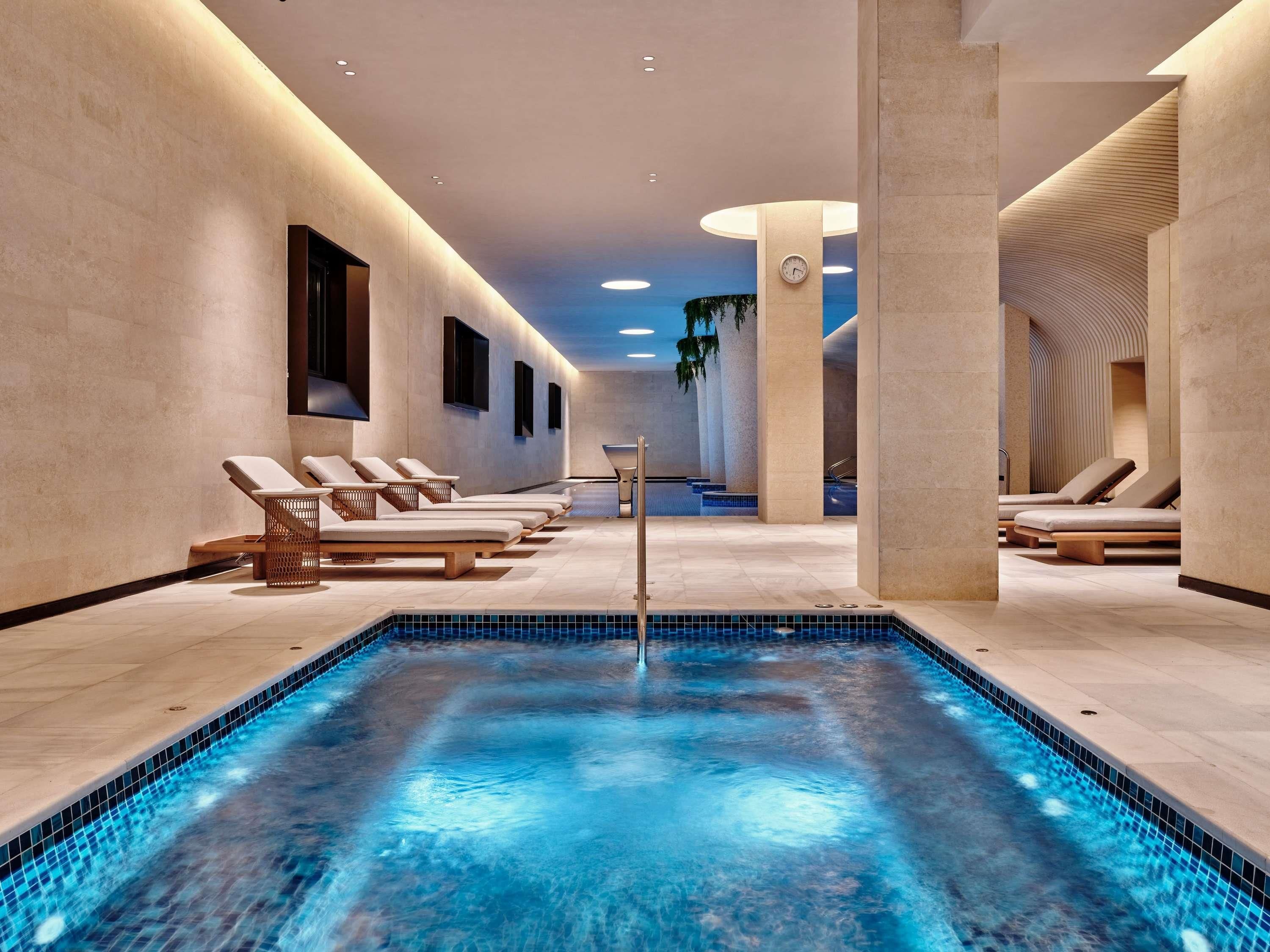 Uma área interna de piscina moderna, com espreguiçadeiras e uma piscina central.