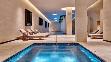 Uma área interna de piscina moderna, com espreguiçadeiras e uma piscina central.