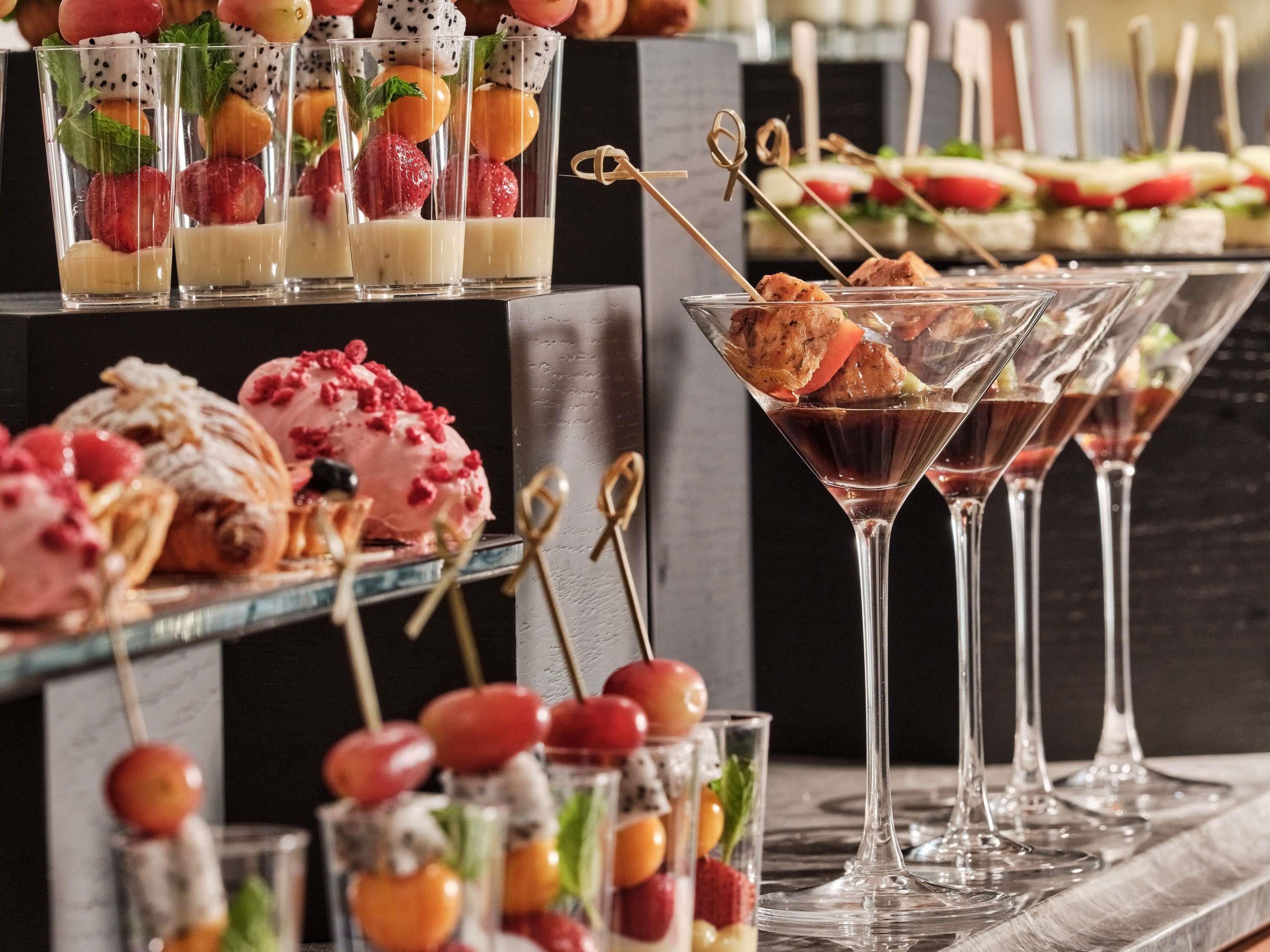 A variety of food and drink offerings, including fruit skewers, desserts, and cocktails.