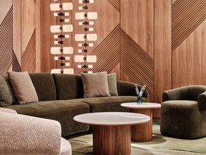 Una sala moderna con un sofá modular, dos mesas de centro redondas y un sillón.