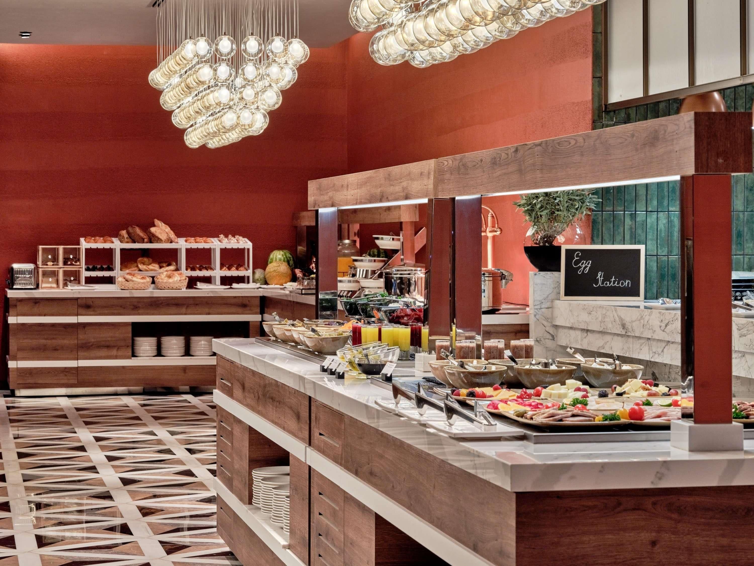 A buffet setup with various food items, a sign indicating an egg station, and a patterned floor.
