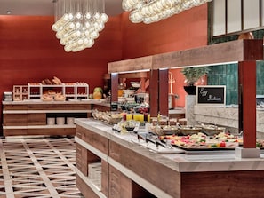 A buffet setup with various food items, a sign indicating an egg station, and a patterned floor. - Swissôtel Tashkent (Tashkent)