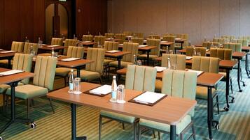 A conference room with rows of tables and chairs, equipped with water bottles and notepads.