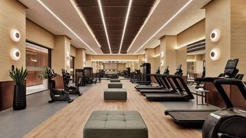 A modern gym with treadmills, elliptical machines, and free weights.