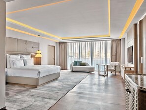 Una habitación de hotel moderna con una cama grande, un sofá, una mesita y un televisor.