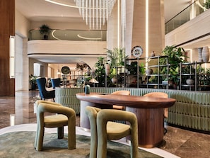 A modern lobby with a central seating area, a high ceiling, and a decorative wall with plants. - Swissôtel Tashkent (Tashkent)