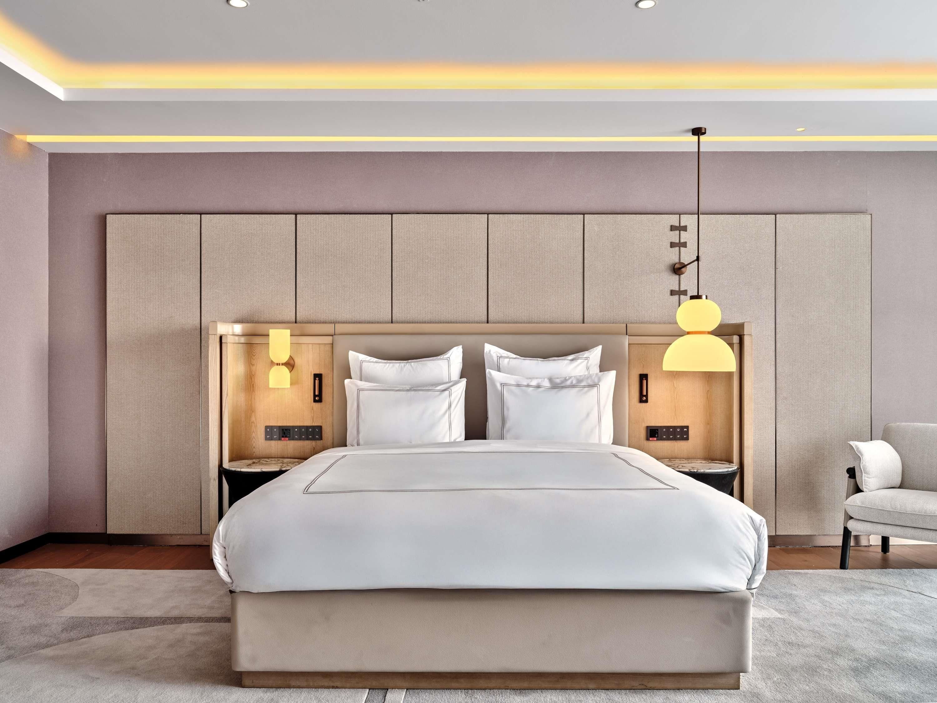 A modern bedroom with a large bed, two bedside tables, and a chair.