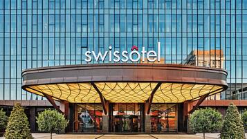 A modern hotel entrance with a glass facade, a prominent sign, and a covered entrance area.
