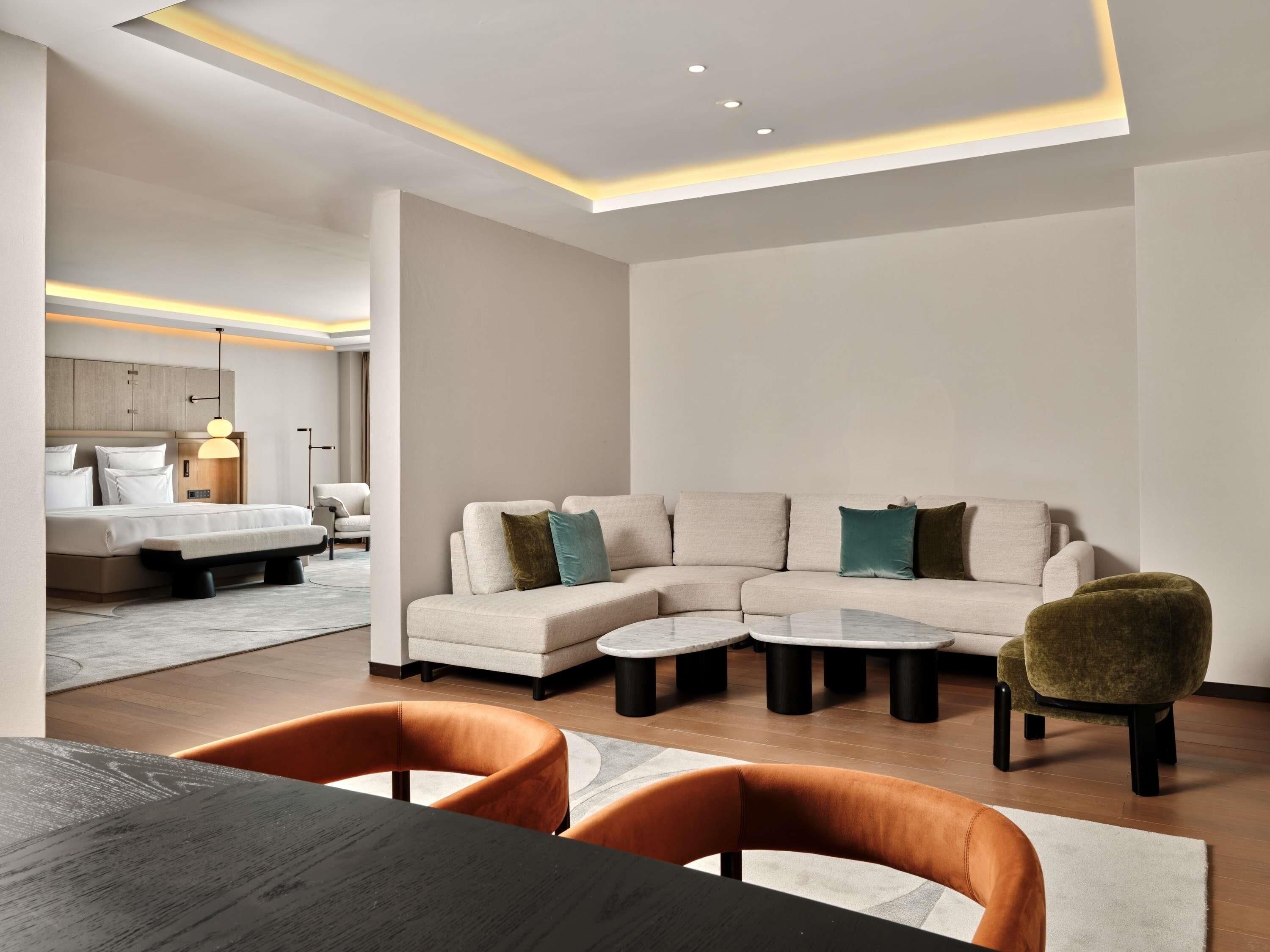 A modern living room with a sectional sofa, a round coffee table, and a dining table with chairs.
