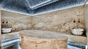 A marble bathroom with a freestanding bathtub, a small sink, and a wall-mounted basin.