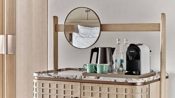 A bathroom with a wooden cabinet, a mirror, a coffee maker, and a kettle.