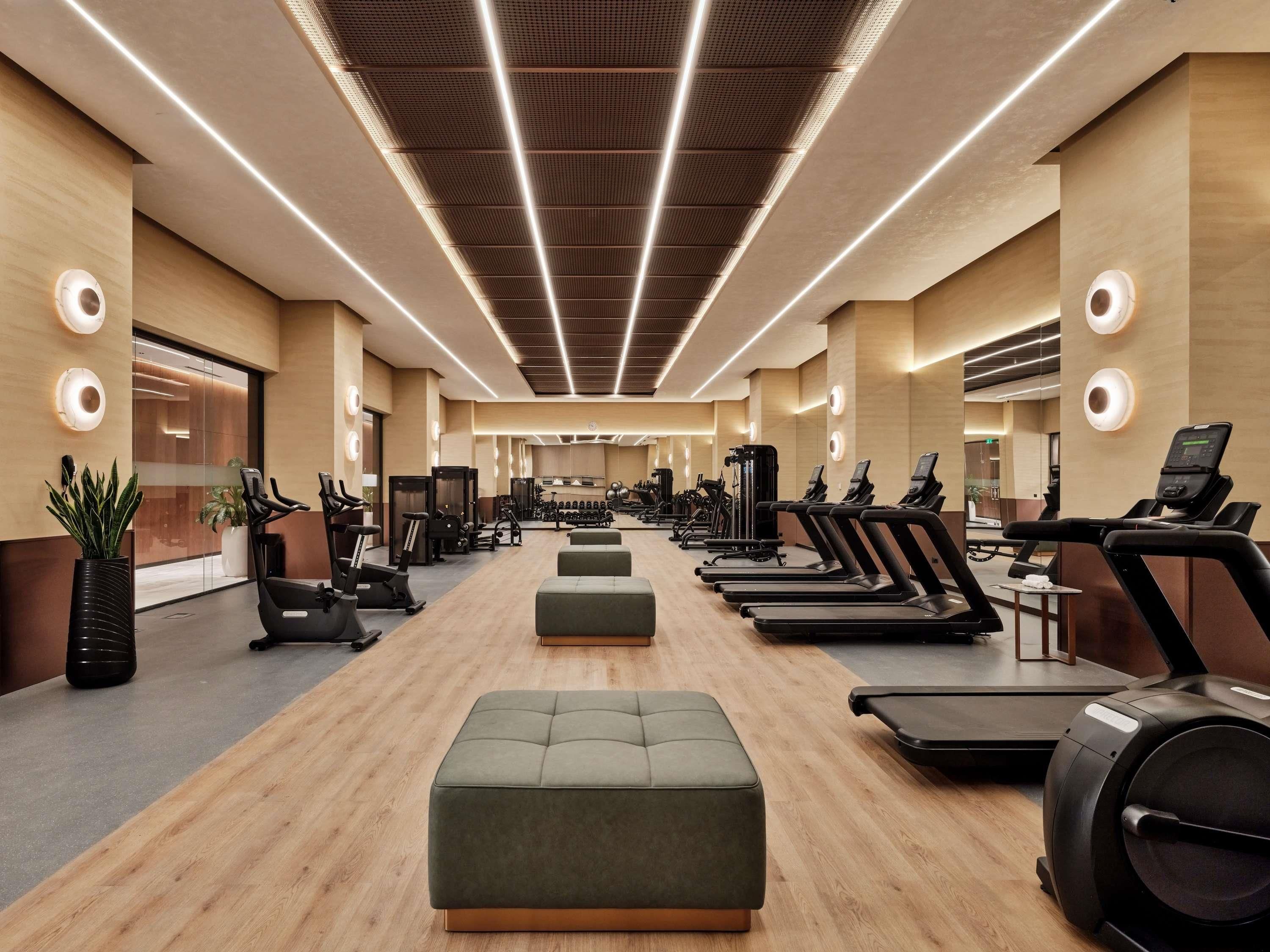 A modern gym with treadmills, elliptical machines, and weight equipment.