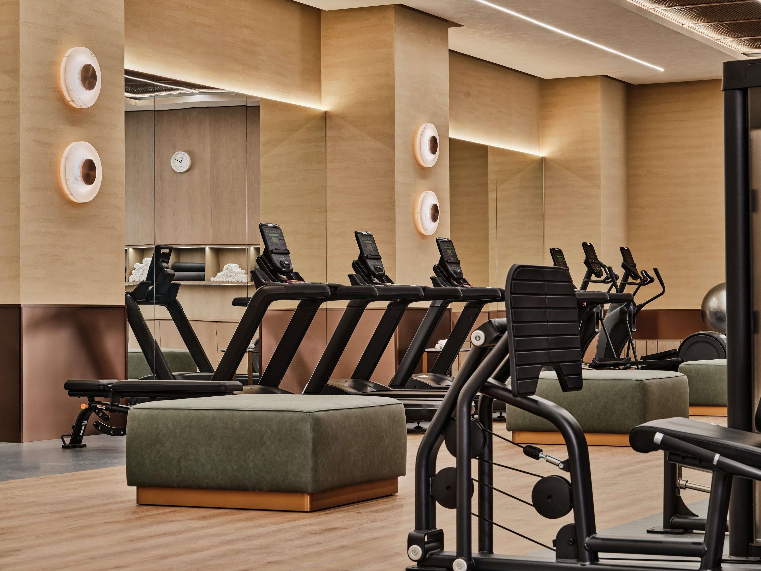 Un gimnasio con cintas de correr, bicicletas estáticas y máquinas de pesas.