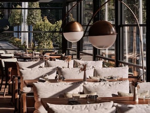 A restaurant with a modern interior, featuring large windows, wooden tables, and comfortable seating. - Swissôtel Tashkent (Tashkent)