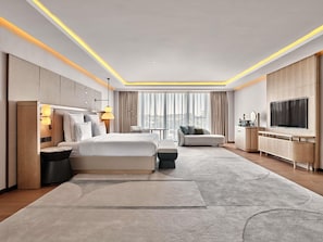 Una habitación de hotel moderna con una cama grande, un sofá, un televisor y un escritorio.