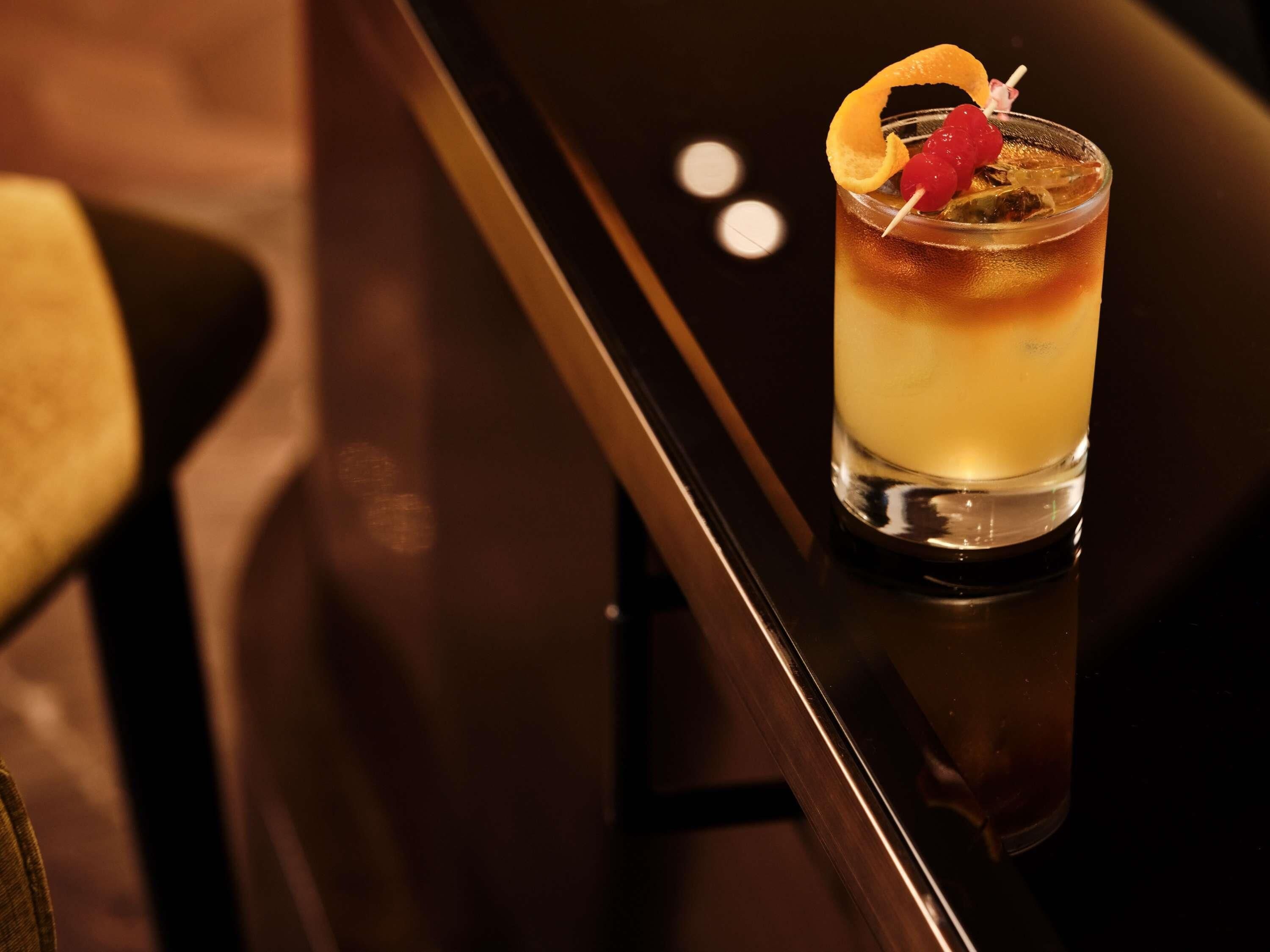 A cocktail with a garnish in a glass on a bar counter.