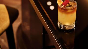 A cocktail with a garnish in a glass on a bar counter.