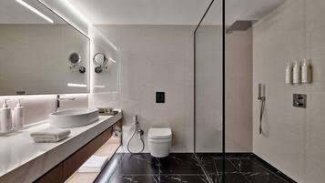 Un baño moderno con un espejo grande, un lavabo redondo, un inodoro y una zona de ducha.
