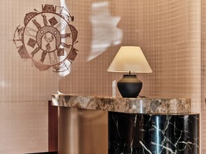 A reception desk with a marble top, a wall clock, and a lamp. - Swissôtel Tashkent (Tashkent)