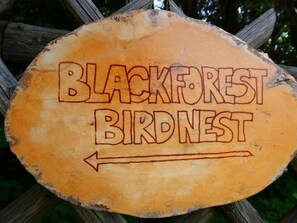 Un panneau en bois portant l’inscription « BLACKFOREST BIRD NEST » et une flèche pointant vers la gauche.