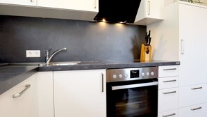 Una cocina moderna con armarios blancos, un horno de acero inoxidable y una encimera negra.