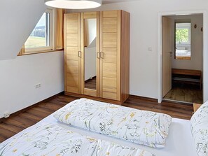 Ein Schlafzimmer mit großem Kleiderschrank, einem Bett mit Blumenmuster und einem Spiegel.