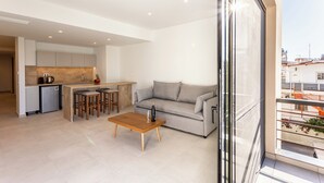 A modern apartment with a kitchen, a living area with a sofa and coffee table, and a balcony with a railing. - Grec Suites Dafni, Athens Supreme Apartment by GrecCollection (Dafni)